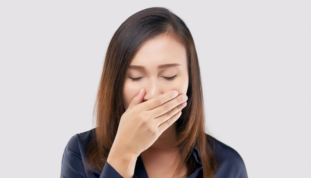 woman suffering from persistent hiccups covering her mouth