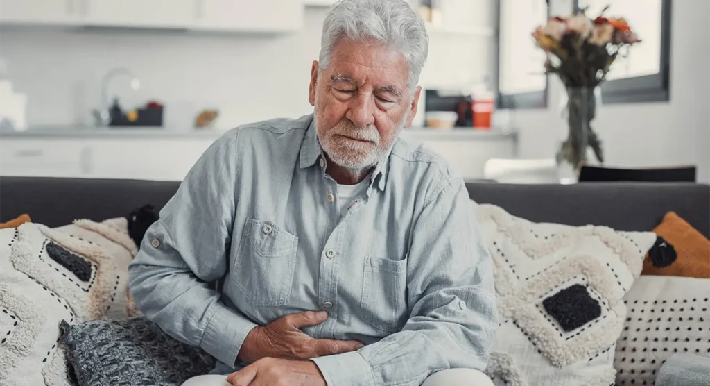 older man holding his stomach in pain from bloating
