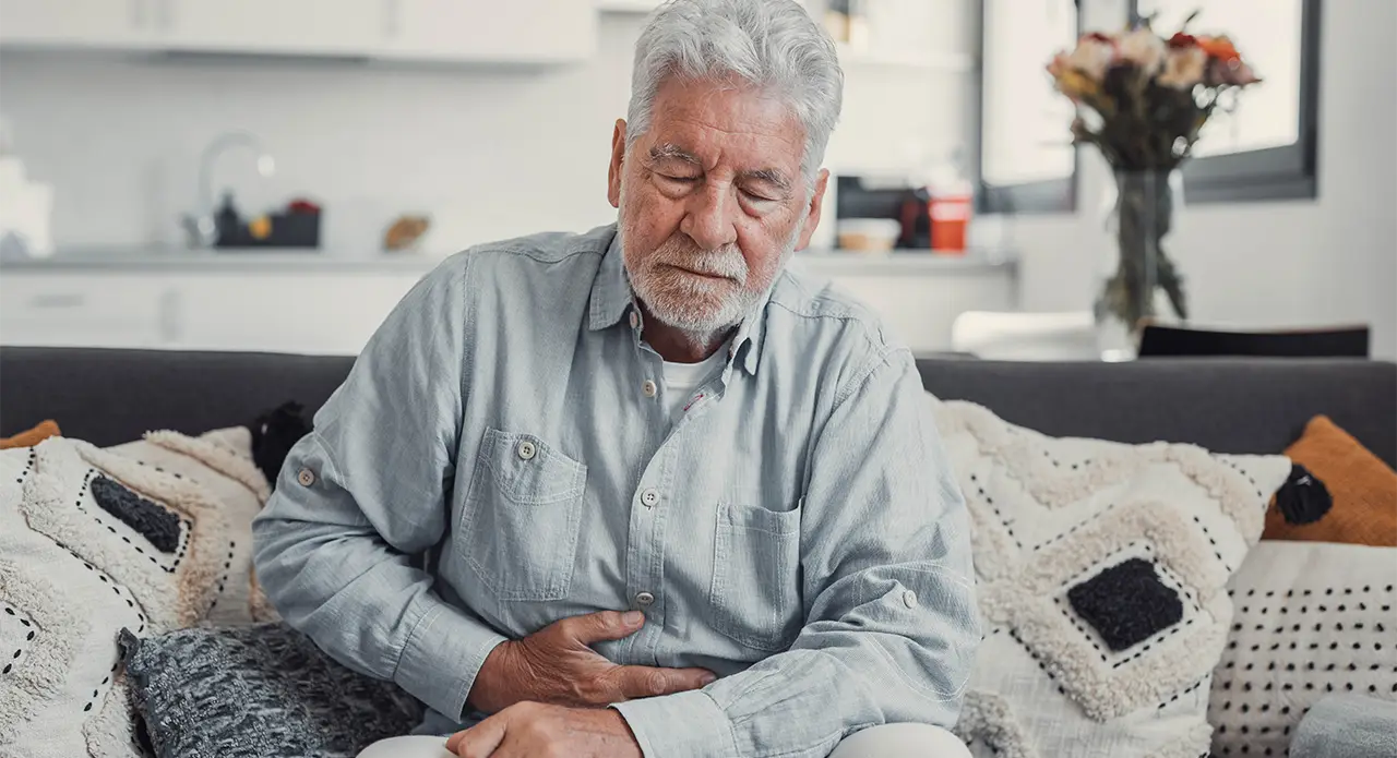 older man holding his stomach in pain from bloating